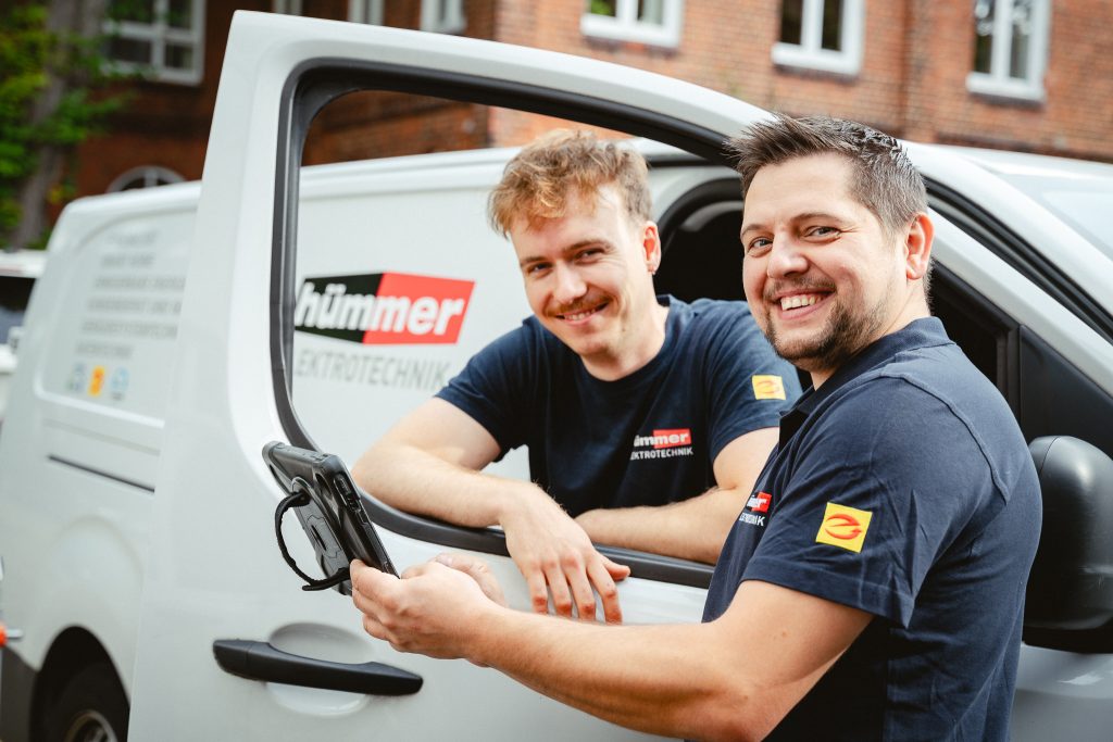 Zwei Monteure stehen am Fenster eines Montagewagens von Hümmer Elektrotechnik